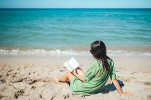 jeune femme lisant un livre pendant une plage blanche tropicale photo