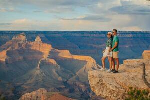 content couple sur une raide falaise prise dans le incroyable vue plus de célèbre grandiose canyon sur une magnifique coucher de soleil, grandiose canyon nationale parc, Arizona, Etats-Unis photo