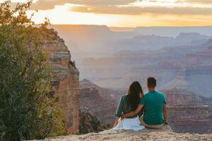 content couple sur une raide falaise prise dans le incroyable vue plus de célèbre grandiose canyon sur une magnifique coucher de soleil, grandiose canyon nationale parc, Arizona, Etats-Unis photo