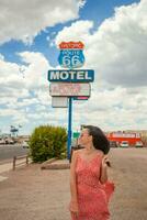 magnifique femme dans rouge robe sur célèbre Autoroute en dessous de populaire signe route 66 photo