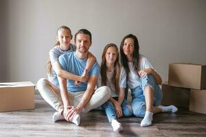 une famille heureuse avec deux filles s'amuse dans leur nouvelle maison. un parent avec des enfants profite de leur journée de déménagement photo