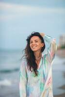 Jeune content femme sur le plage prendre plaisir sa été vacances. femme en marchant le long de le mer dans soir. photo