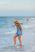magnifique adolescent fille sur tropical rivage en marchant à peu profond l'eau et ayant amusement photo