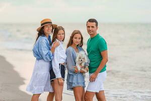 famille de quatre avoir amusement ensemble sur plage vacances à le coucher du soleil photo