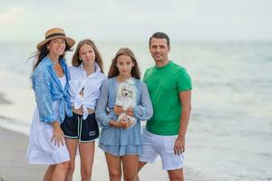 famille de quatre ensemble sur plage vacances à le coucher du soleil photo