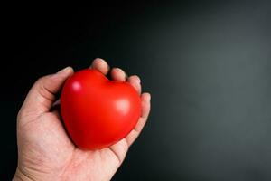 main en portant Vide rouge cœur sur foncé Contexte. une symbole de l'amour ou sortir ensemble photo
