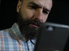homme élégant avec une barbe et une moustache regarde un téléphone portable