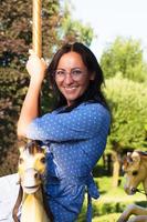 fille heureuse dans le parc sur un manège, en été photo