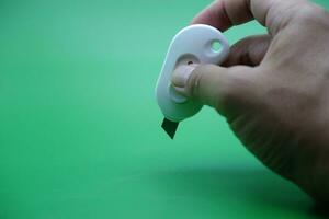 main en portant une blanc coupeur isolé sur une vert Contexte. photo