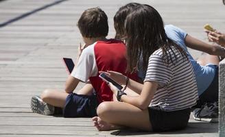 Enfants accrochés à des appareils électroniques dans le parc de Madrid Rio, Madrid Espagne photo