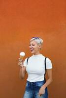 en riant Jeune femme avec la glace crème cône dans de face de Orange Contexte photo