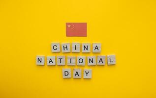 octobre 1, nationale journée dans Chine, le drapeau de Chine, une minimaliste bannière avec un une inscription dans en bois des lettres sur un Orange Contexte photo