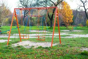 balançoire sur le terrain de jeux entouré par verdure, une magnifique et confortable parc pour le entier famille. photo