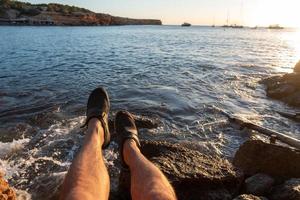 jeune homme profite du coucher de soleil sur le rivage de la plage de cala saona photo