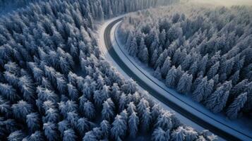 aérien vue de courbée venteux route dans neige couvert forêt. génératif ai photo