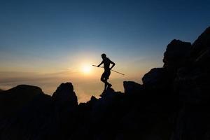 Sky runner en silhouette au coucher du soleil parmi les rochers photo