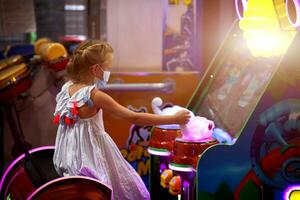 une peu fille dans une médical masque pièces une Jeu machine dans le enfants chambre. photo