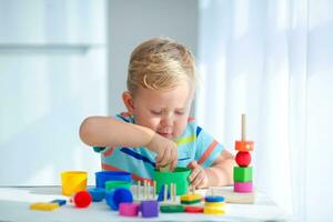 peu garçon 2 ans vieux est joué avec une couleurs jouets. éducatif logique jouets pour les enfants. montessori Jeux pour enfant développement. photo
