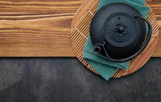 théière en fonte noire avec tisane sur fond de pierre sombre photo