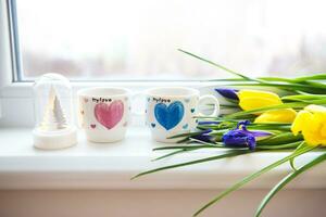 magnifique fleurs-tulipes et Iris mensonge sur le rebord de fenêtre avec deux tasses de café photo