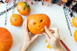 Halloween octobre 31. le pas à pas processus de sculpture une citrouille. le fille coupes le visage de le citrouille avec une couteau. vue de au-dessus de. photo