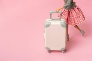 le poupée porte une valise sur roues. voyage, vacances Créatif minimaliste concept photo