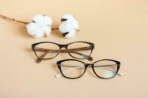 élégant lunettes avec coton sur beige Contexte. optique magasin, vision test, élégant des lunettes concept. photo