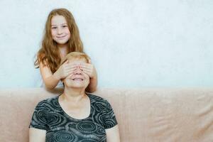 une peu fille permanent derrière sa grand-mère se ferme sa yeux avec sa mains photo