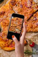 femelle main fabrication une photo de Pizza avec une mobile téléphone