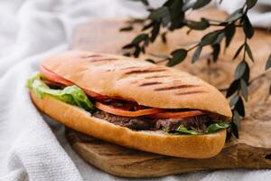 sandwich avec Viande et des légumes sur une en bois planche photo