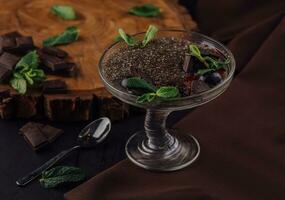 Chocolat mousse dessert avec pruneaux et menthe feuilles dans portion des lunettes photo