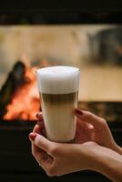 une femelle main en portant une tasse de café contre cheminée photo