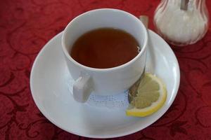 une tasse blanche avec du thé sur la table avec une rouge. photo