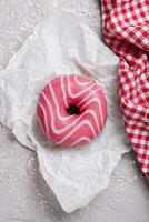 fraise Donut couvert avec rose glaçage sur cuisson papier photo