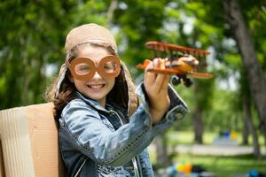 une peu fille sur vacances à le parc avec une pilote tenue et en volant équipement. courir autour et avoir amusement avec sa rêves. photo