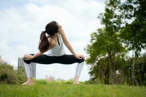 Jeune femelle avec Extérieur Activités dans le ville parc, yoga est sa choisi activité. photo