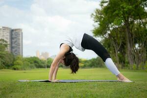 Jeune femelle avec Extérieur Activités dans le ville parc, yoga est sa choisi activité. photo