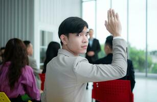 portrait de une Jeune asiatique homme d'affaire séance derrière une séminaire pièce avec une collègue dans le premier plan écoute à le conférence photo