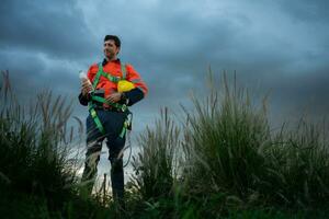 portrait de une Jeune homme travail dans vent turbine champ, portant une sécurité gilet, le concept de se détendre temps après travail photo