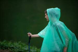 fille dans imperméable avec en marchant bâton sur le Contexte de le Lac photo