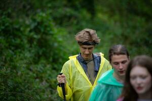 groupe de copains dans imperméables en marchant sur le forêt chemin, randonnée concept. photo