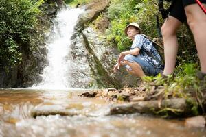 Jeune couple promeneur avec une sac à dos permanent dans de face de une cascade photo