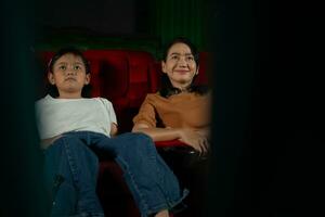 asiatique mère et fille en train de regarder film dans cinéma. famille temps concept. photo