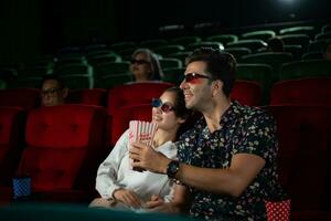 dans une cinéma, une Jeune couple paire portant 3d des lunettes montres films et mange Popcorn. photo