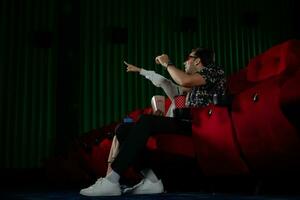 Jeune homme et femme en train de regarder film dans cinéma, séance sur rouge des places photo