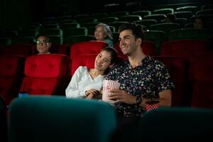 Jeune homme et femme en train de regarder film dans cinéma, séance sur rouge des places photo