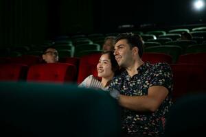 Jeune homme et femme en train de regarder film dans cinéma, séance sur rouge des places photo