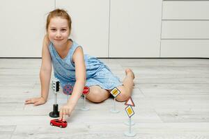 mignonne peu fille en jouant à Accueil sur le sol avec une machine à écrire, route panneaux et circulation lumières photo