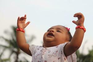 mignonne asiatique bébé fille en jouant avec sa mains en haut et souriant photo