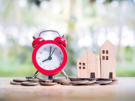 temps est argent concept. rouge alarme et miniature maison. le économie concept pour maison et propriété. photo